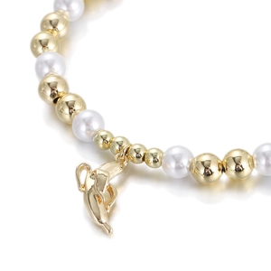 Macro detail of gold beads and white pearls bracelet featuring a gold dolphin charm
