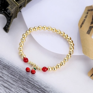 Detail of beaded bracelet featuring gold copper beads and a red cherry charm