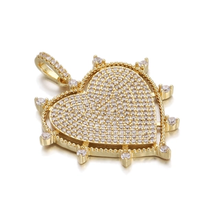 Macro shot of gold heart pendant featuring cubic zirconia pavé setting and radial spikes