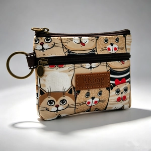 Dettaglio portamonete in tela beige con stampe di gatti, doppia cerniera e logo in pelle