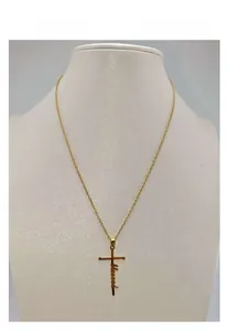 Detail of gold stainless steel necklace with a blessed letter cross pendant on neck model