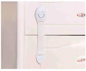 White child safety strap lock installed on a cabinet drawer to prevent opening