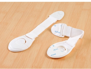 Detail of white child safety locks with fabric straps and 3M adhesive on wood surface