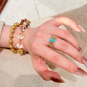 Nahaufnahme eines eleganten Goldspitzenrings mit Türkisstein und Armbändern