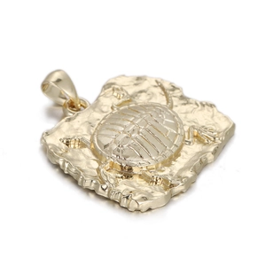 Detailed macro view of a golden turtle pendant with intricate shell on a textured base