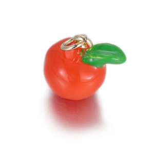 Detail van rode emaille appelhanger met groen blad en gouden ring voor DIY-sieraden
