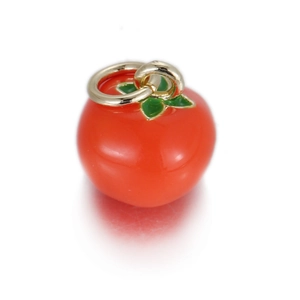 Macro-opname van een rode tomaat hanger met groene bladeren en gouden ring voor DIY sieraden