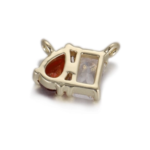 Détail d'un pendentif doré avec zircon rouge en poire et pierre rectangulaire transparente
