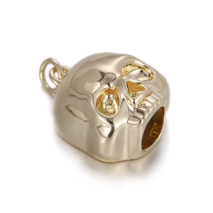Detailed macro view of a golden skull pendant with hollow eyes and punk dinosaur fossil style