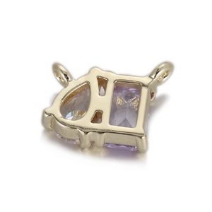 Détail macro d'un pendentif D doré avec zircon violet et anneaux de connexion