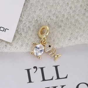 Gold sea turtle and fish bone charms with zircon inlay on white lace background