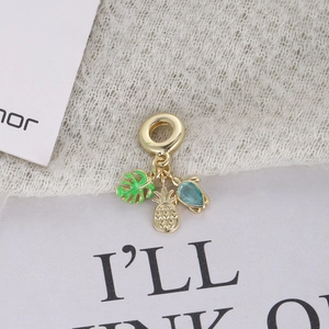 Detail of tropical gold charms featuring green enamel leaf, pineapple and turtle with blue stone