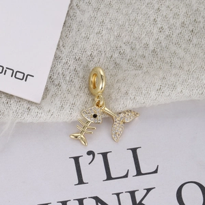 Detailed close-up of a fishbone and fishtail charm with white cubic zirconia in gold