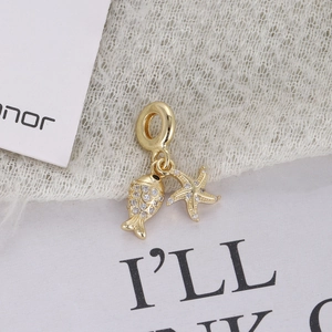 Macro shot of gold-plated marine pendants featuring a star and fish with zircon stones