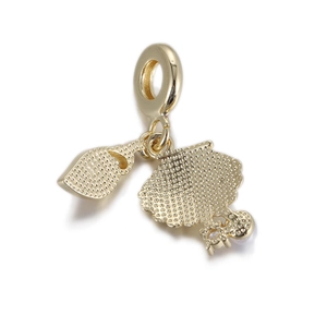 Close-up of a gold-plated charm featuring a miniature spoon and doll pendant with white zircons