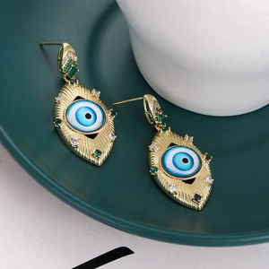 Macro shot of gold evil eye stud earrings with green rhinestones and enamel detail
