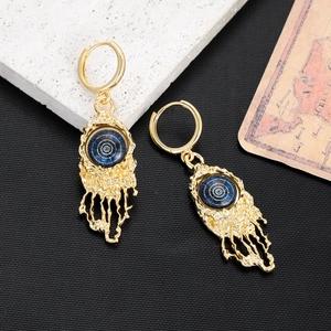 Close-up of gold evil eye earrings with blue details and unique lava texture finish