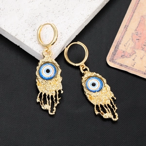 Close-up of golden Evil Eye hoop earrings with irregular lava texture and blue stones