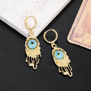 Detail of gold evil eye tassel earrings with vintage lava texture and turquoise beads