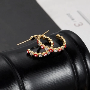Detailed view of gold C-shaped earrings with evil eye motifs and sparkling cubic zirconia