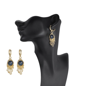 Golden evil eye earrings with blue textured disks and liquid gold fringe on a model