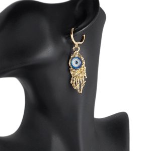 Golden evil eye earrings with skeleton claw tassels on a black model bust jewelry display