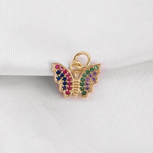 Detailed close-up of a golden butterfly pendant with colorful zircon stones on white silk