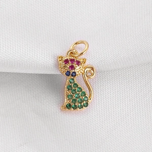 Macro shot of gold cat pendant with vibrant green and red gemstones on silk fabric