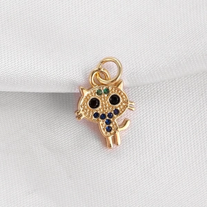 Detailed view of cat pendant with blue and green crystals on gold-plated metal
