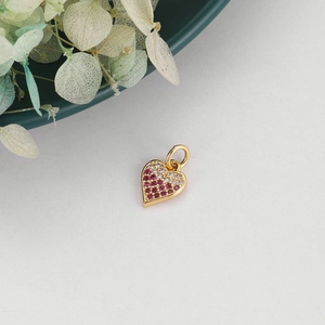 Detailed close-up of a gold heart pendant with pink and white pavé-set stones on white background