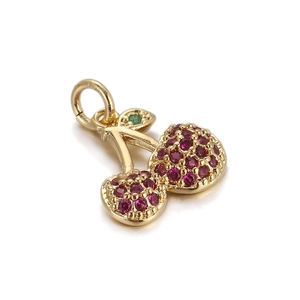 Detail of a gold cherry pendant with red crystal inlay and green leaf gemstone