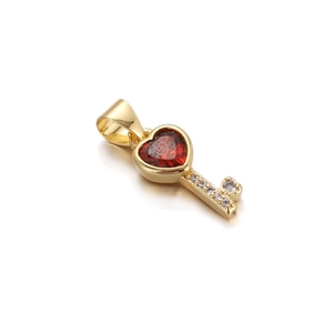 Detail of a golden key pendant featuring a red heart gemstone and sparkling diamond accents