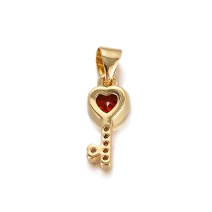 Detailed close-up of golden heart key pendant featuring a vibrant red heart-shaped gemstone