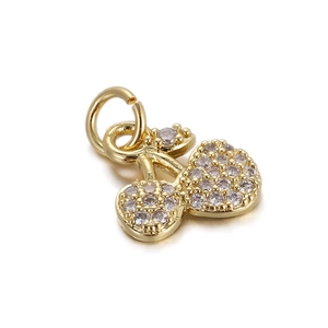 Macro detail of a gold cherry charm pendant with white zircon stones and round metal loop