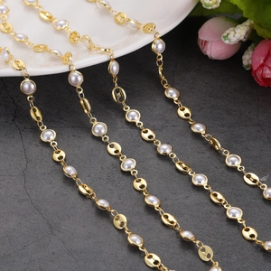 Detail view of 18K gold-plated pig nose chain links and white pearls on a stone surface