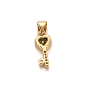 Macro shot of gold heart key pendant with green gemstone and sparkling white zircons