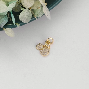 Detailed view of cherry pendant with gold plating and cubic zirconia on white surface
