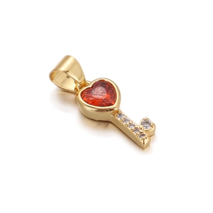 Detail showing golden heart key pendant with red gemstone and white crystal inlay