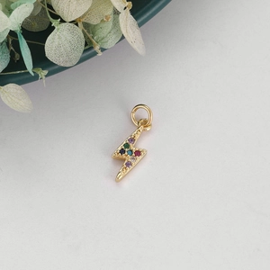 Macro detail of lightning bolt pendant featuring colorful cubic zirconia on gold metal