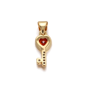 Detailed view of a gold heart key pendant with a faceted red gemstone inlay