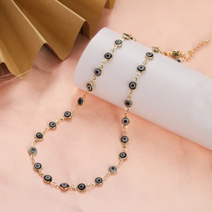 Close-up of golden stainless steel Evil Eye necklace on elegant pink satin background