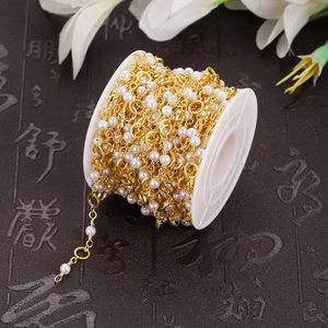 Detailed view of DIY jewelry chain with white faux pearls and gold metal links on a spool