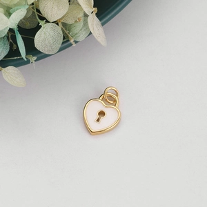 Macro shot of white heart lock charm with gold alloy edges and enamel inlay detail