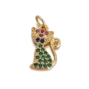 Macro shot of gold cat pendant with green and purple gemstones on white backdrop