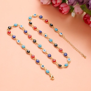Dettaglio di bracciali con occhio del male dorati e perline colorate su sfondo rosa