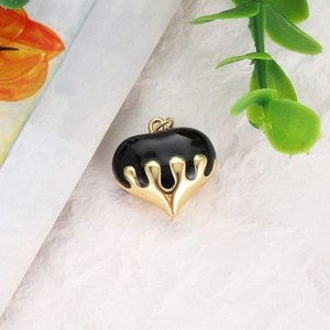 Macro shot of heart-shaped gold-plated copper pendant with black drip oil enamel detail