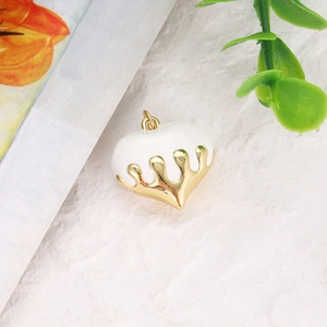 Macro view of heart charm pendant with white enamel drip effect and gold plated finish