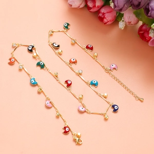 Dettaglio macro di braccialetti dorati con ciondoli Evil Eye turchi colorati e strass