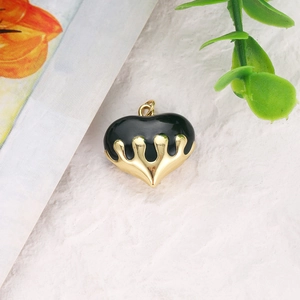 Detailed view of heart charm with black enamel and molten gold metal dripping edges