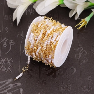 Macro shot of gold star frame and pearl bead chain for DIY jewelry making on a white spool